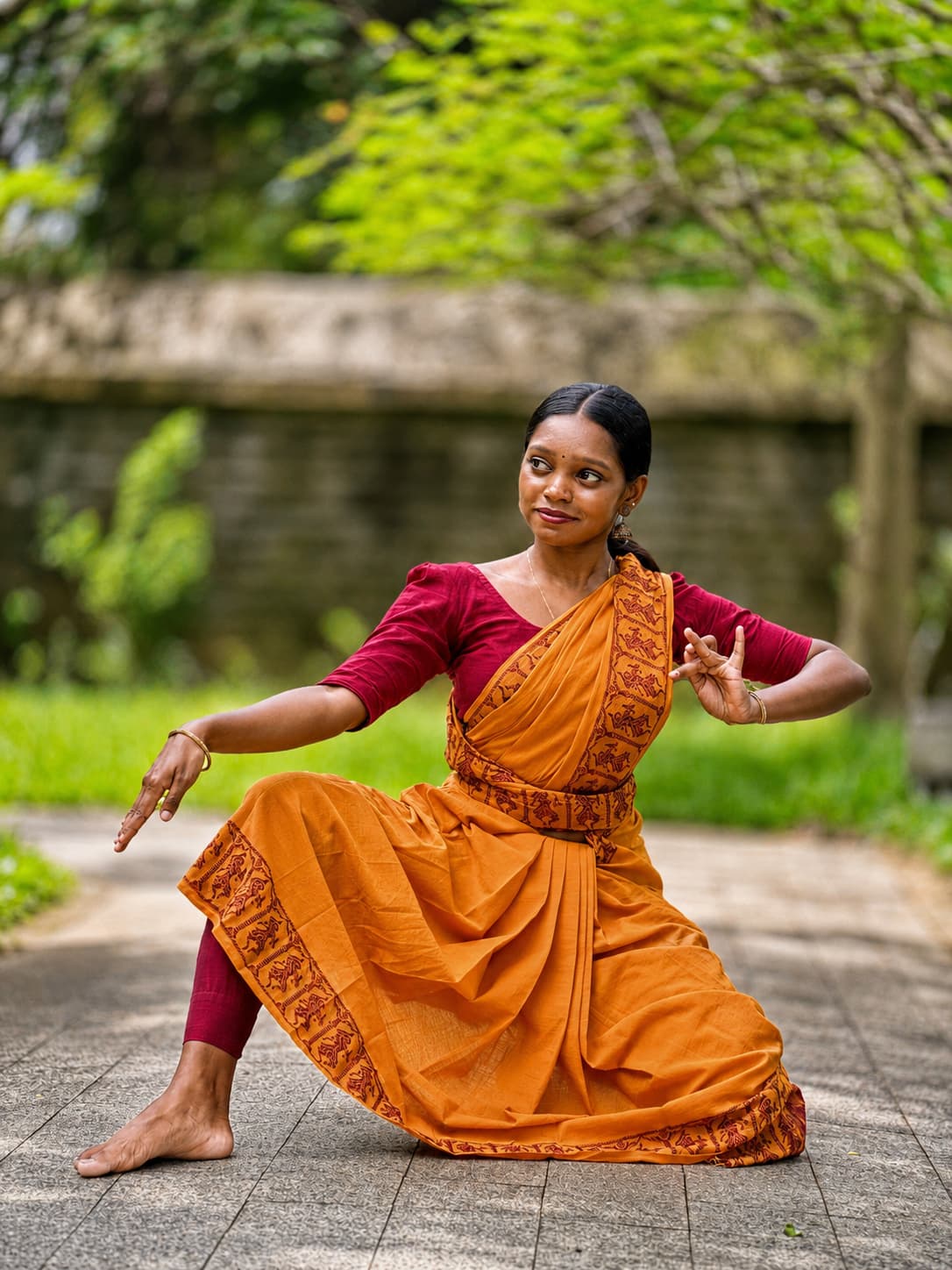 Lakshmi Kumaran in a deep aramandi pose on an outdoor stone walkway
